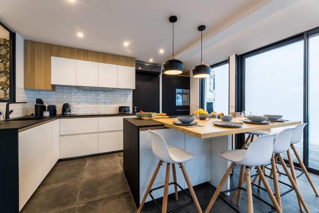 a kitchen with white cabinets and a counter with stools at BLOOMY - Villa Biarritz in Biarritz