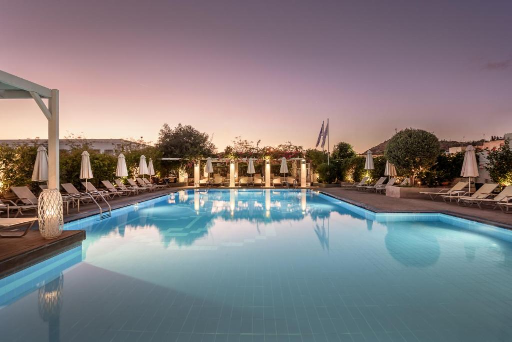 a large swimming pool with chairs and umbrellas at Nissia Kamares in Kardamaina
