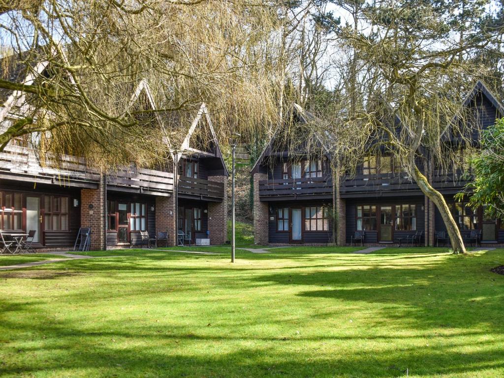 a building with trees in front of a grass yard at Bittern Lodge in Cromer