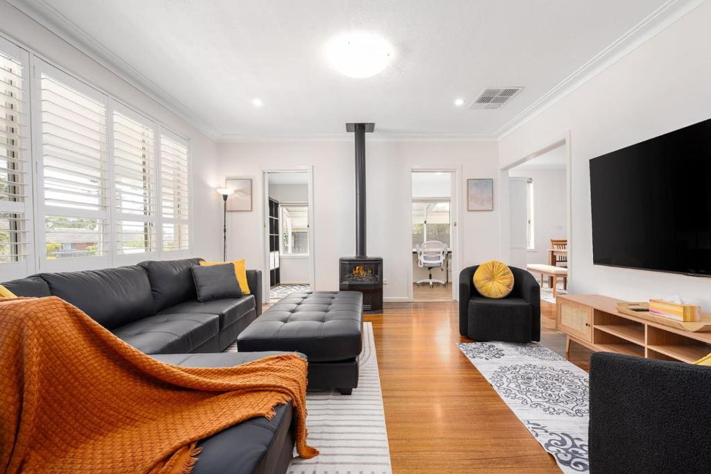 a living room with a couch and a flat screen tv at Spacious Multifunctional 5BR Retreat with Backyard in Bayswater