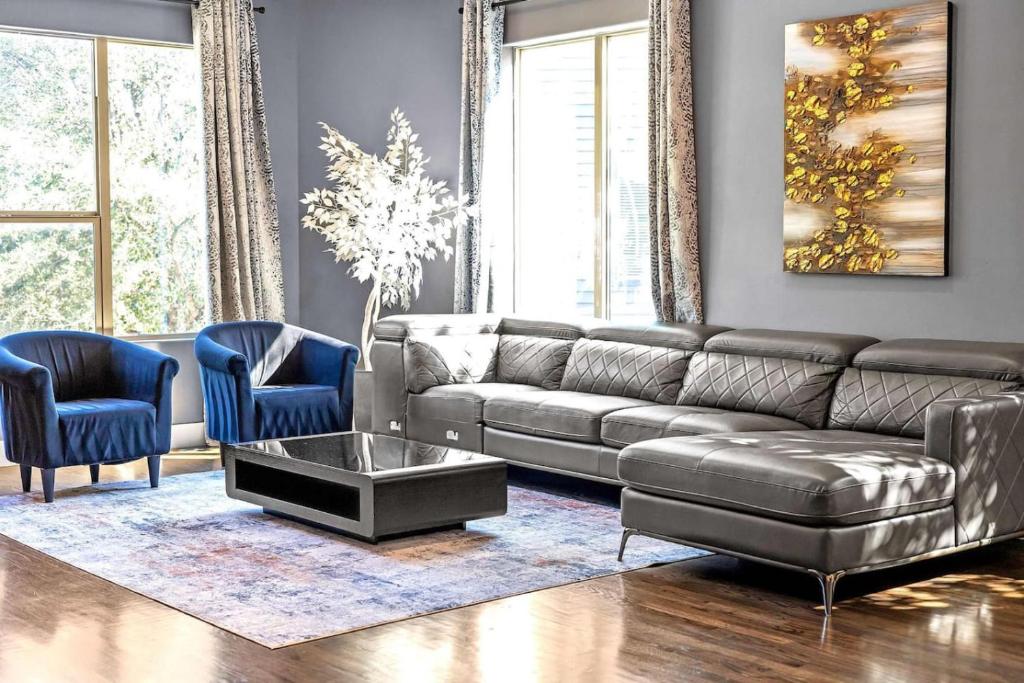 a living room with a leather couch and two blue chairs at King-Sized Comfort with Rooftop Skyline Views in Dallas