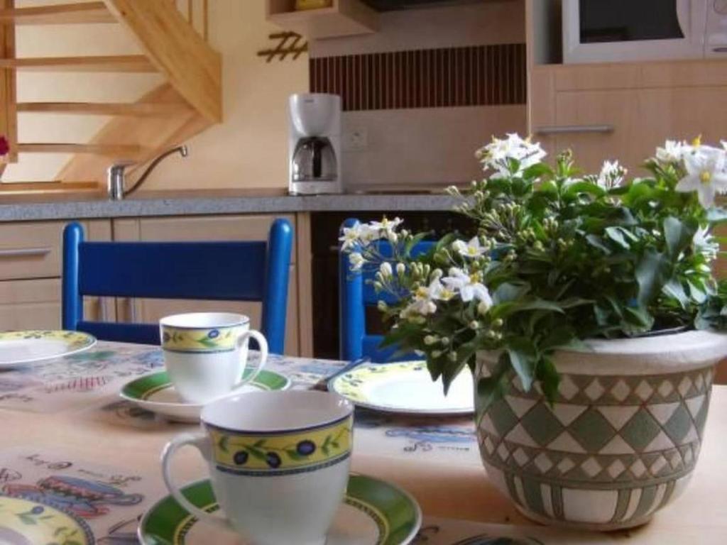 a table with two cups and a vase with flowers at Friesenhus in Butjadingen
