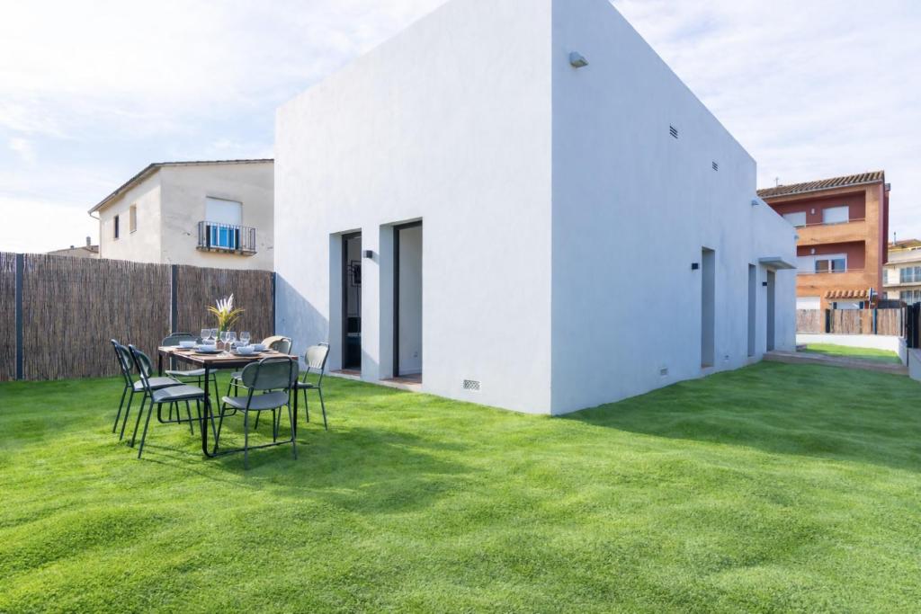 a white house on a lawn with a table and chairs at Jouvacations Villa Osona in Vilafant