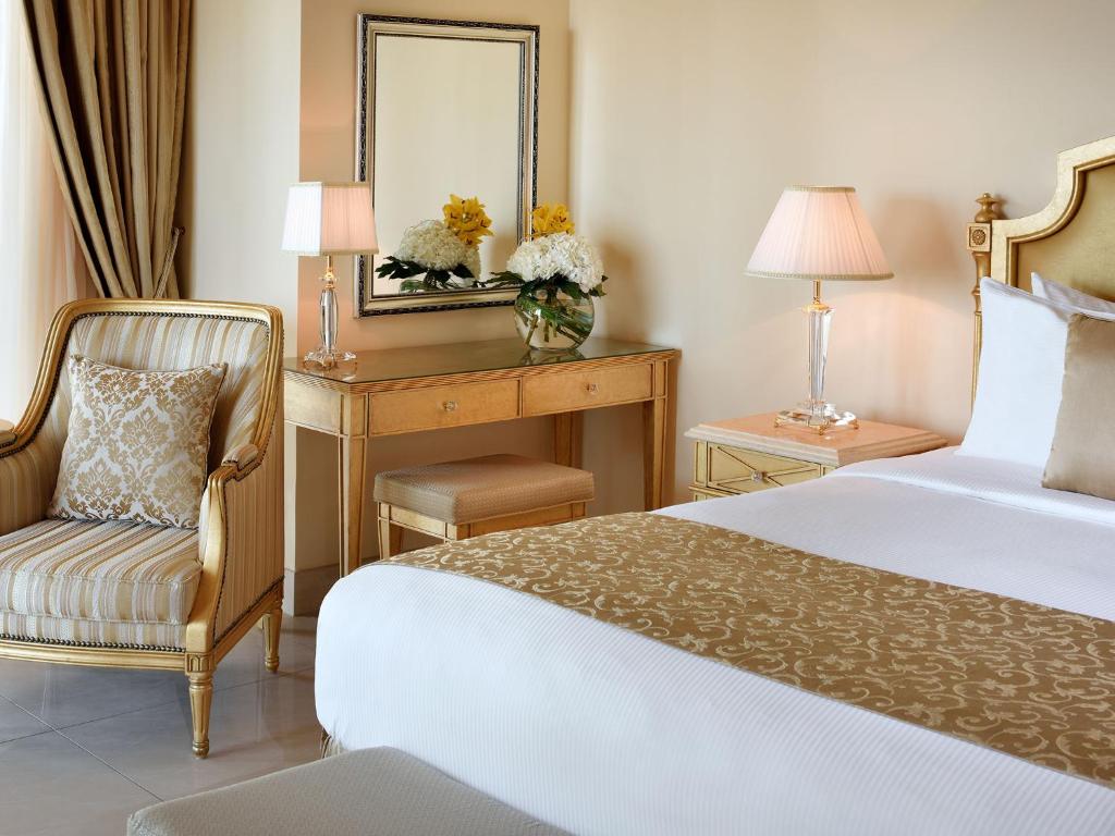 a bedroom with a bed and a desk with a mirror at Kempinski Hotel Palm Jumeirah in Dubai