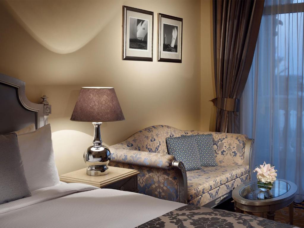a bedroom with a bed and a couch and a lamp at Kempinski Hotel Palm Jumeirah in Dubai