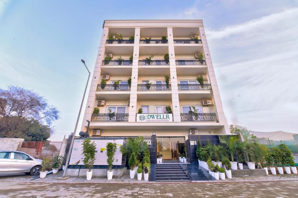 ein hohes Gebäude mit Topfpflanzen davor in der Unterkunft Dwellr Luxury Stays - Golf Course Road in Gurgaon