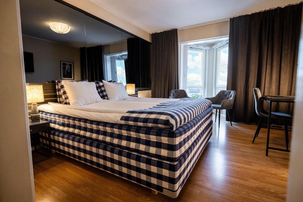 a bedroom with a bed with a checked blanket on it at Hotell Gillet i Köping in Köping