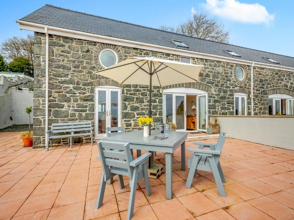 a table and chairs and an umbrella on a patio at Golygfa Hudol - Uk46712 in Pwllheli