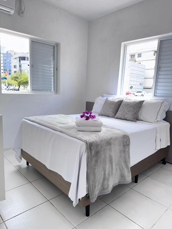 a white bedroom with a large white bed with flowers on it at Hotel Tropical in Torres