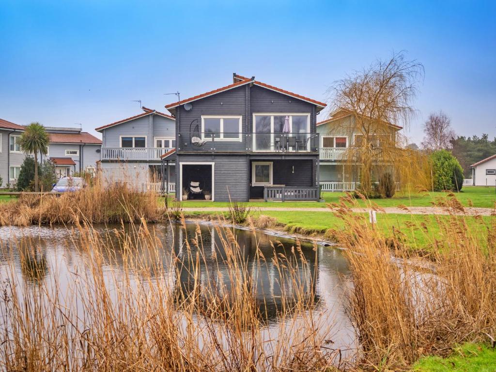 a large house with a pond in front of it at Finest Retreats - Oasis 41 in Fritton