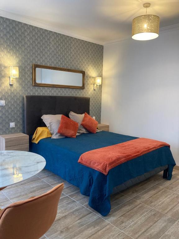 a bedroom with a blue bed with colorful pillows at Studio Vintage avec cheminée décorative in Villefranche-sur-Saône