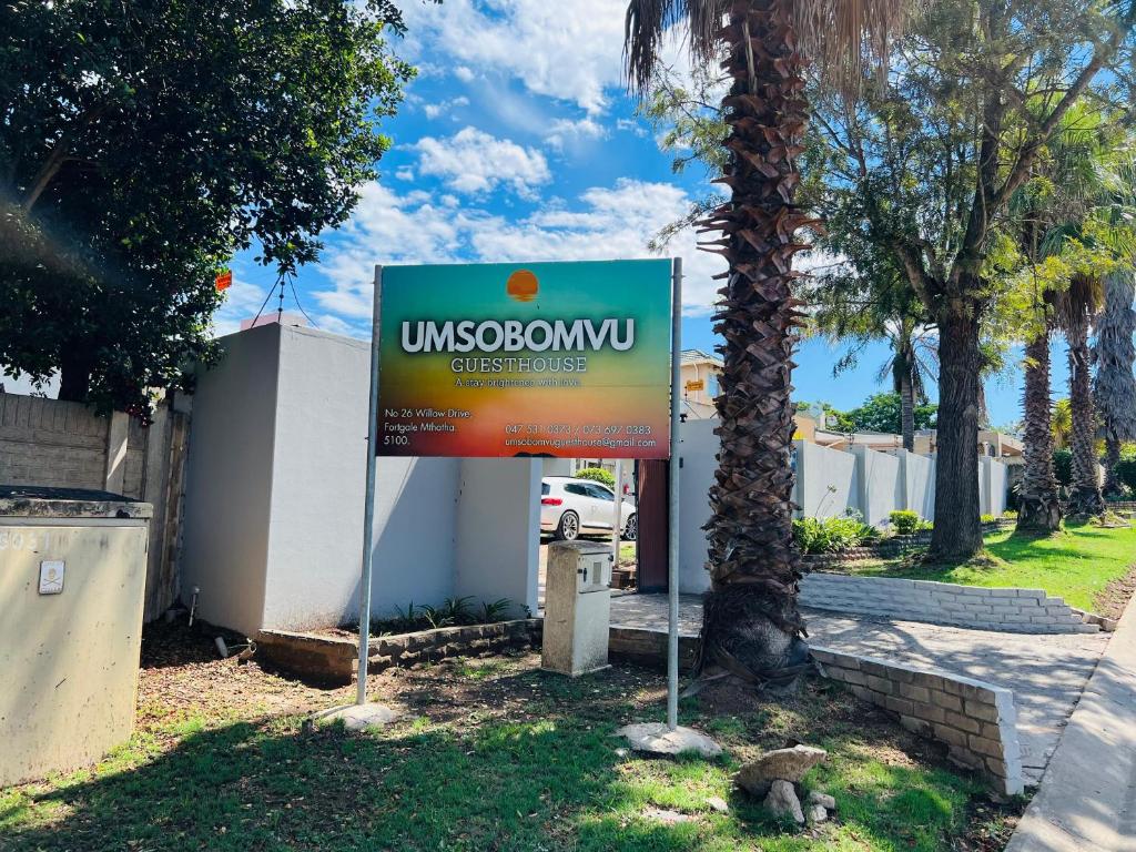 a sign in the grass next to a building at Umsobomvu Guest House in Mthatha