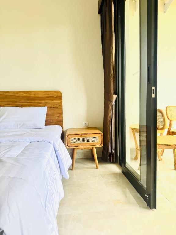 a bedroom with a bed and a bench next to a window at Umah Kak Pasek in Jimbaran
