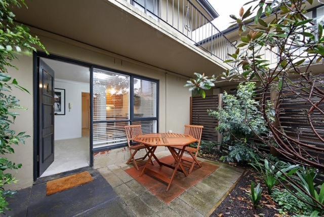 a patio with a wooden table and chairs next to a building at Moonya Courtyard in Carnegie