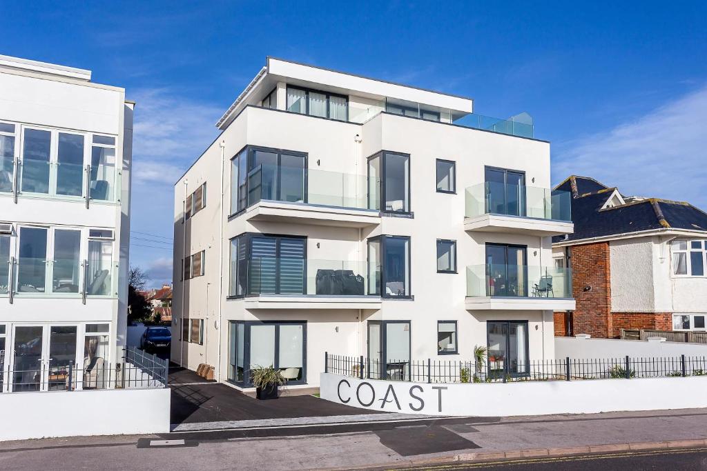 a white building with a coast sign in front of it at Beachcliff - On the Seafront with Two Balconies in Bournemouth