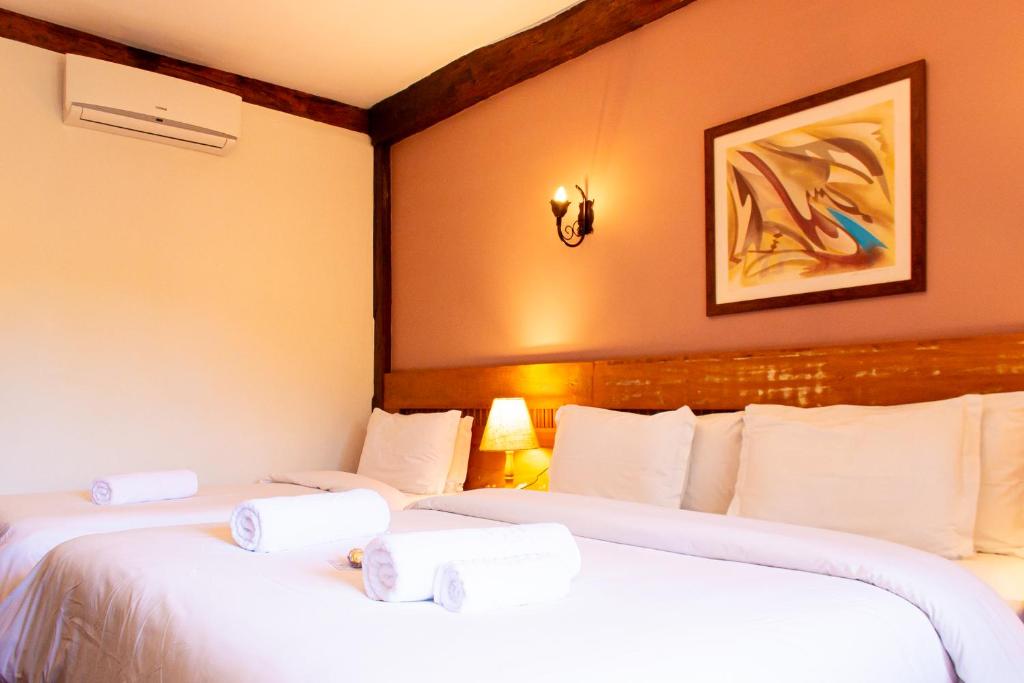 two beds in a hotel room with white sheets at Pousada Chão de Minas in Cachoeira do Campo
