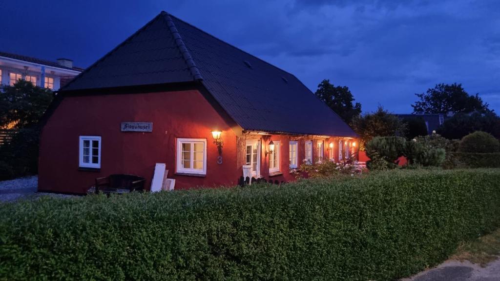 a red house with a black roof at night at Stouwhuset Øster Hurup in Hadsund