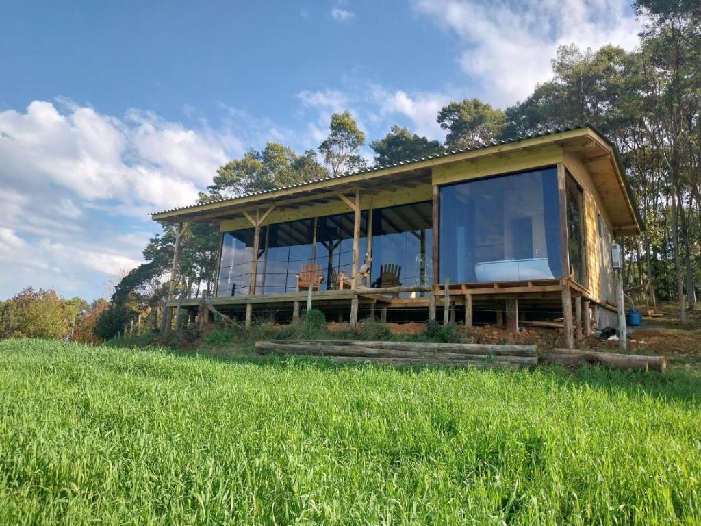 a house with glass windows on a field of grass at Cabanas do Arvoredo in São José do Cerrito