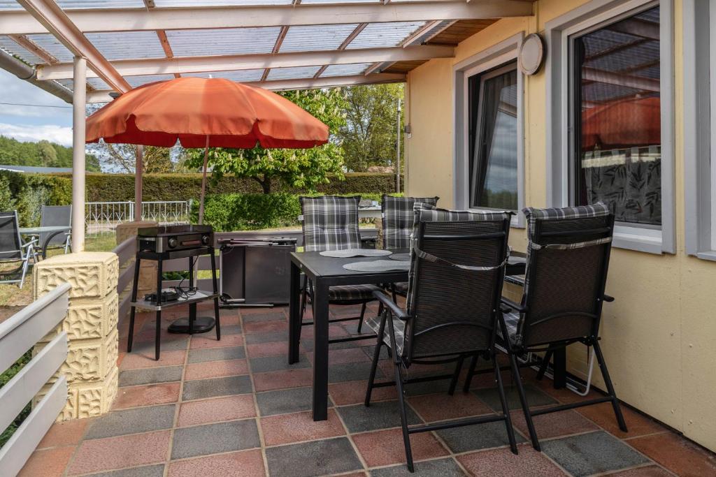 a patio with a table and chairs and an umbrella at Ferienhaus Jupiter im Sternenpark in Lochow