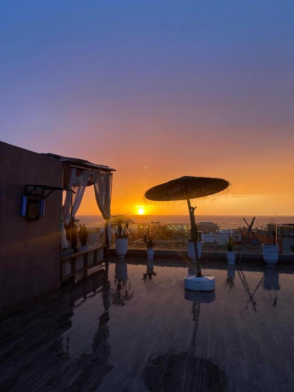 a sunset over the ocean with a large umbrella at Abrid Surf in Tamraght Ouzdar