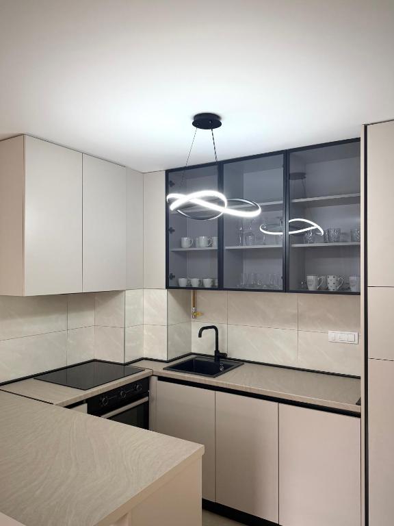 a kitchen with white cabinets and a sink at Apartman 307 in Lukavica
