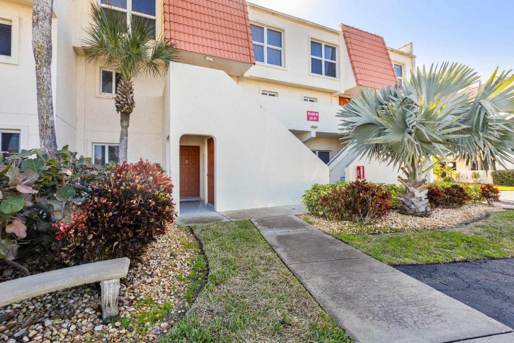 a building with palm trees and a bench in front of it at Pier Point South Ocean View Condo B-22 in St. Augustine