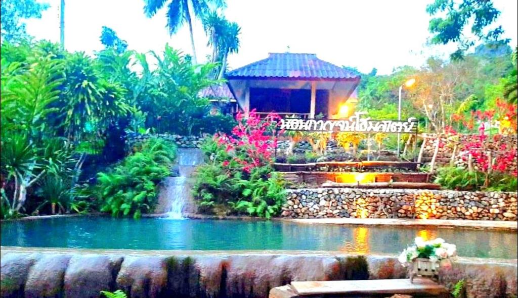 a garden with a pond in front of a building at NonKan HomeStay นอนกาญจน์ โฮมสเตย์ in Ban Plai Huai Kaeng Riang