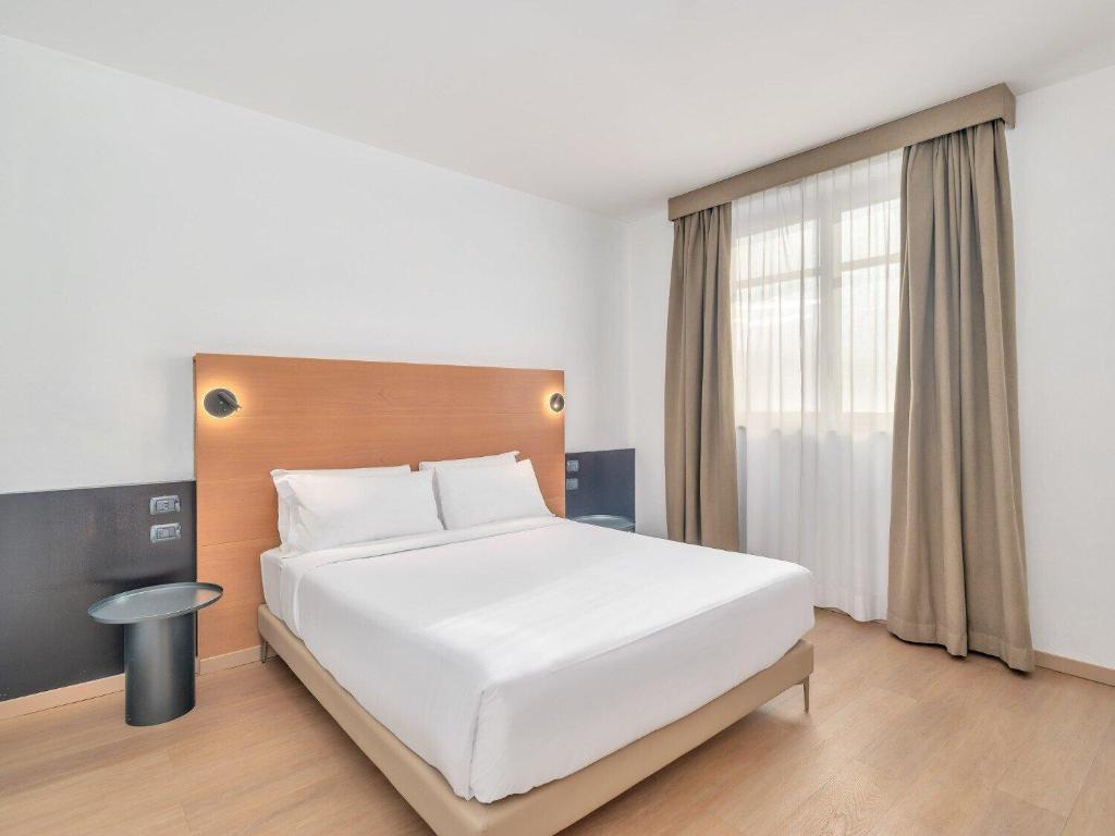 a bedroom with a white bed and a window at B&B HOTEL Milano Cologno Studios in Cologno Monzese