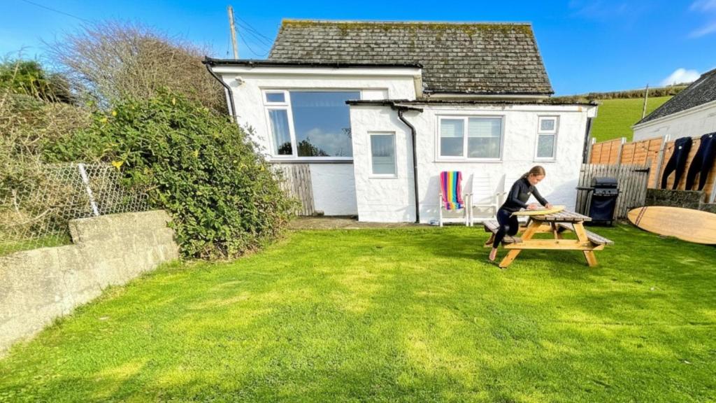 a woman sitting on a picnic table in a yard at CROYDE SEAGRASS 2 Bedrooms in Croyde