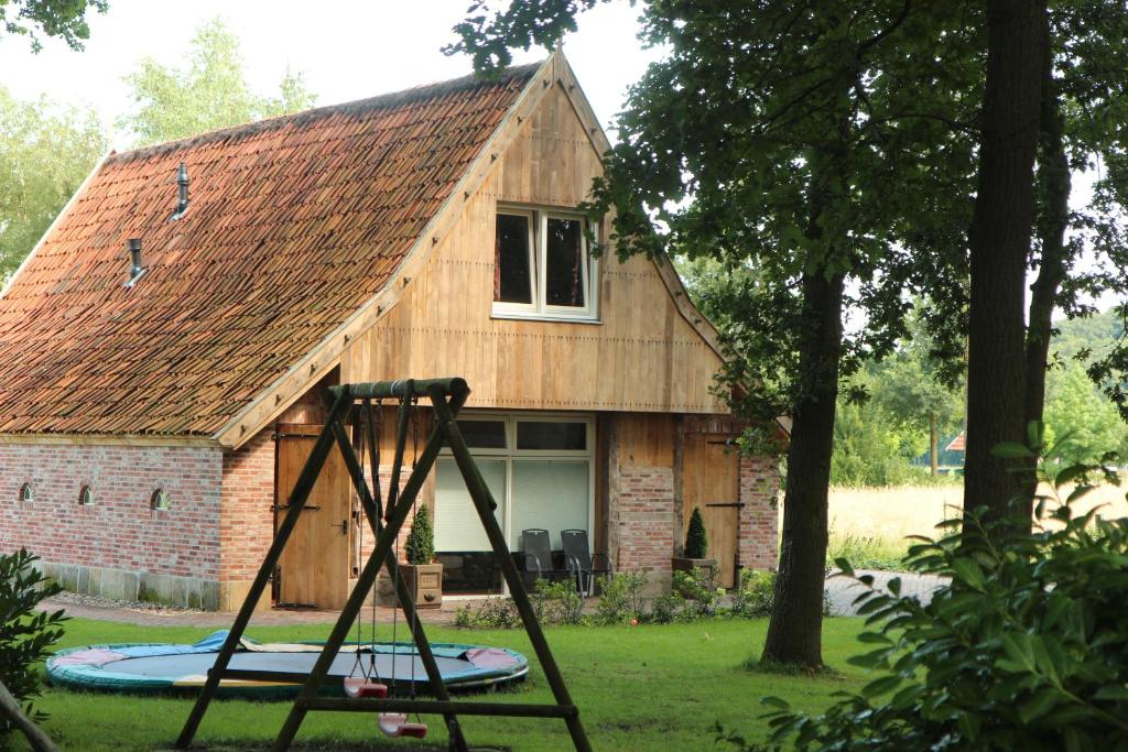 a log cabin with a swing in front of it at Scholtenhoes in Hezingen