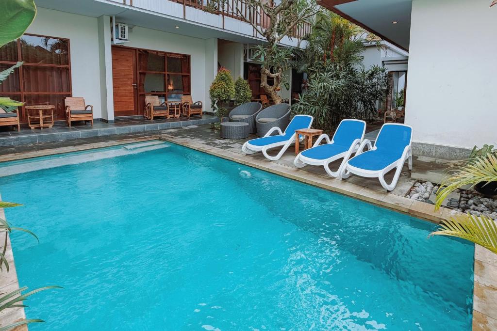 a swimming pool with blue chairs and a house at Moonlight Sanur in Sanur