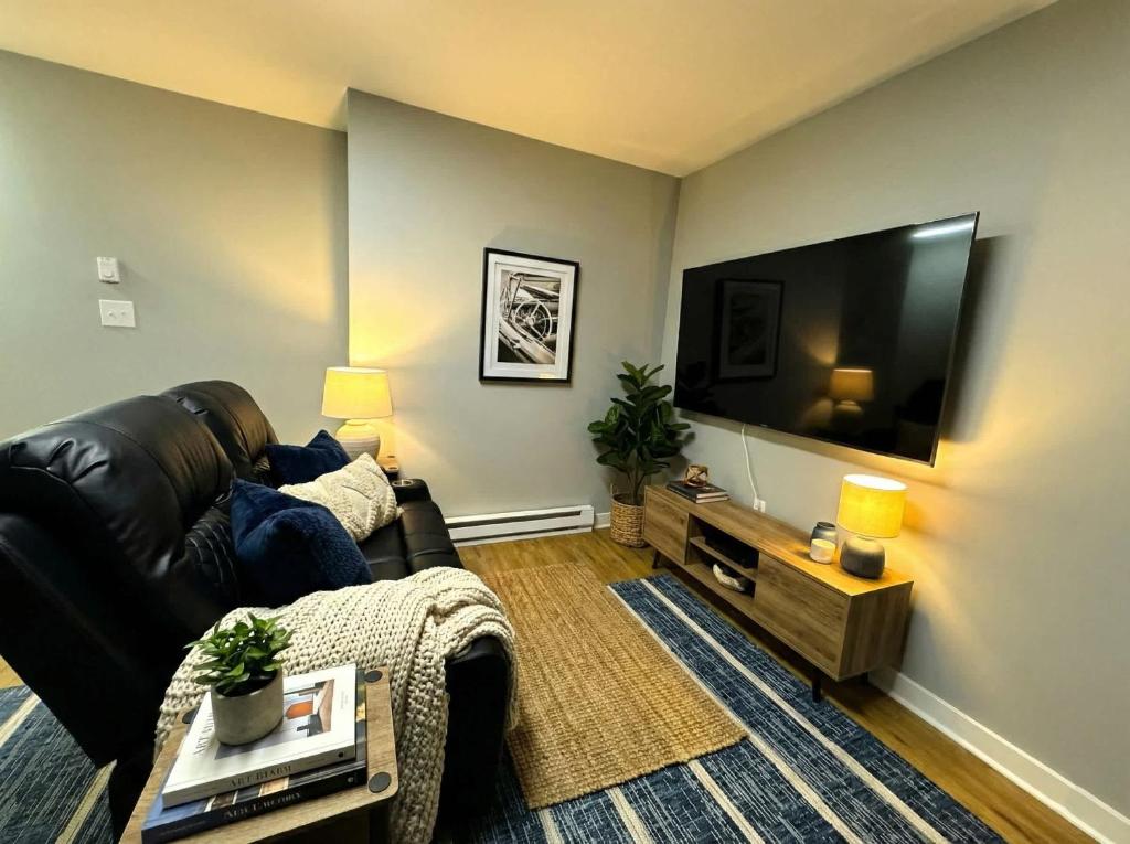 a living room with a black leather couch and a flat screen tv at Crossroads at Park Place in Wilmington