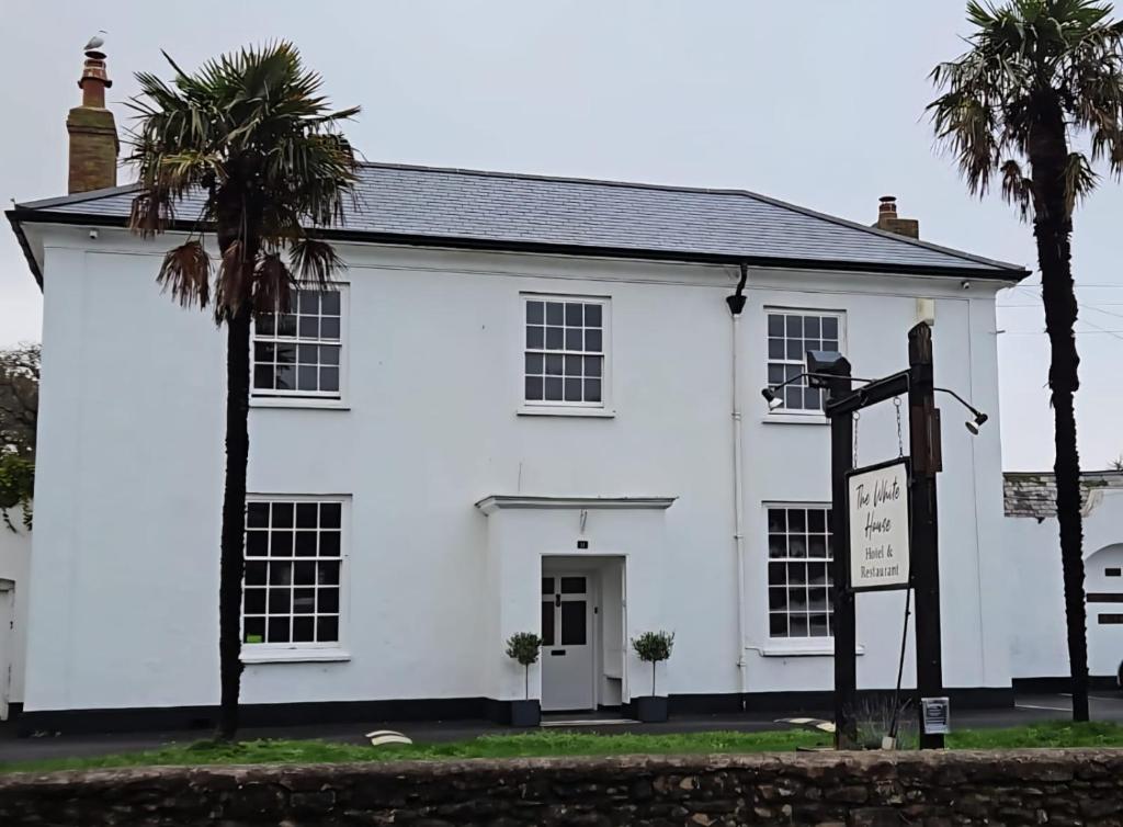 a white house with two palm trees in front of it at The White House Hotel in Williton