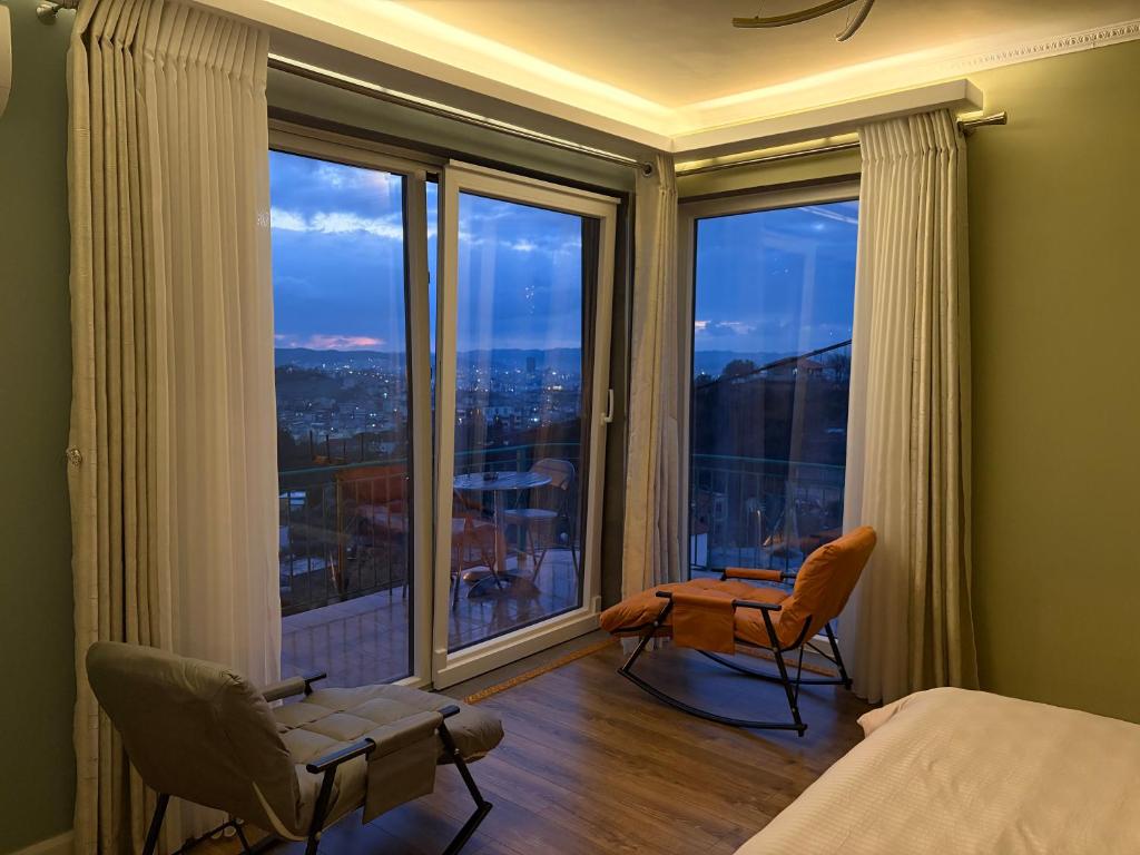 a bedroom with a bed and two chairs and large windows at Tirana SkyView in Tirana