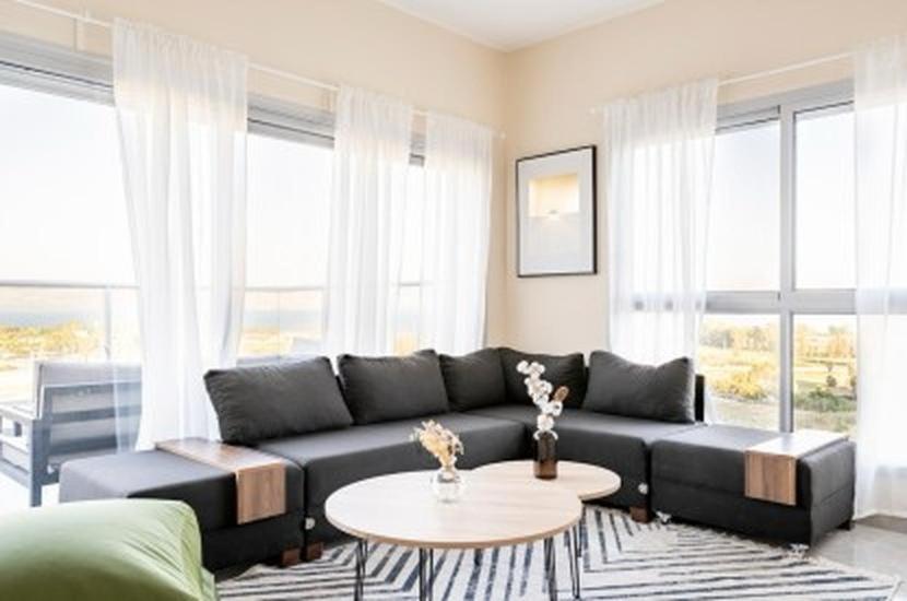a living room with a black couch and a table at וילה קלמה מגדל in Migdal