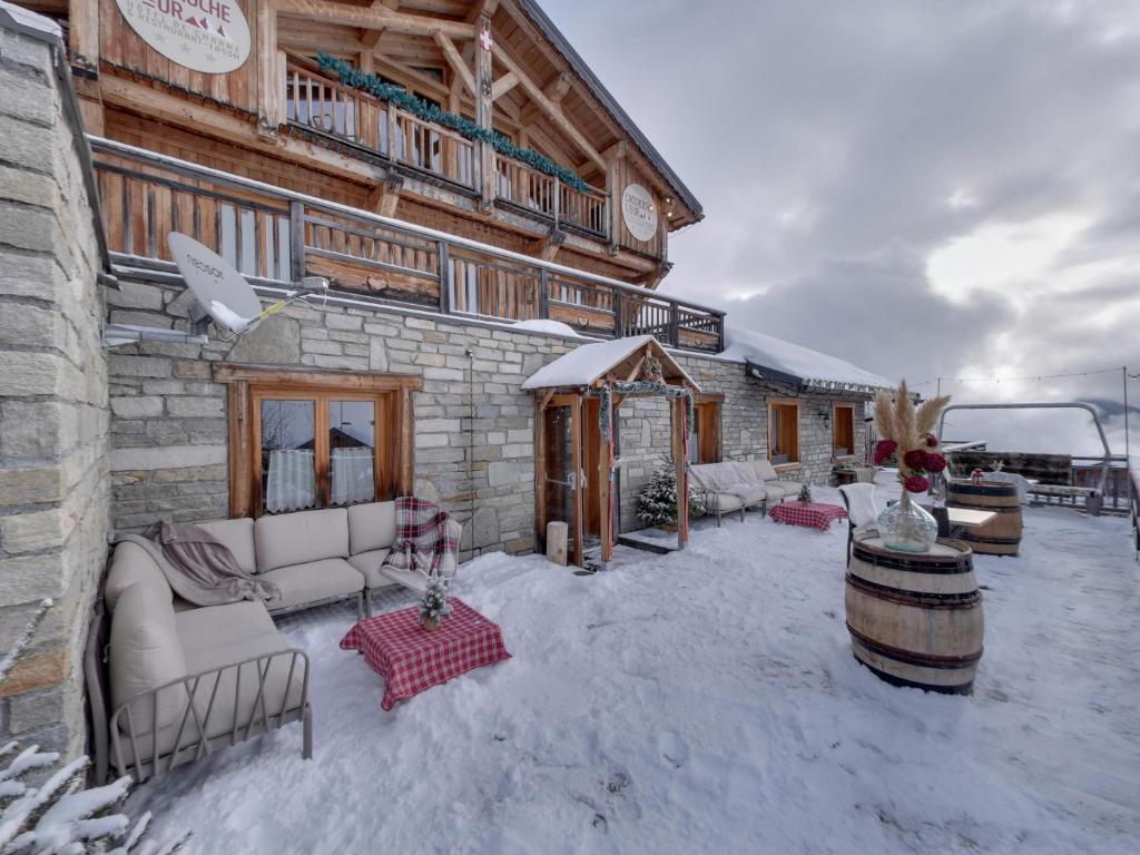a patio with couches and a building in the snow at Hôtel L'Accroche Coeur in La Rosière
