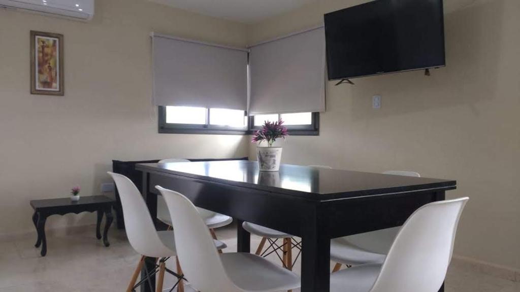 a dining room with a black table and white chairs at paraíso lomas in San Antonio de Arredondo