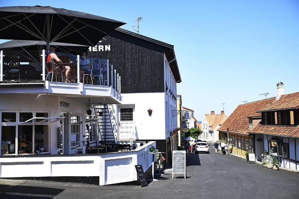 a man sitting on a balcony of a building with an umbrella at Klippen Hotel - Therns in Gudhjem