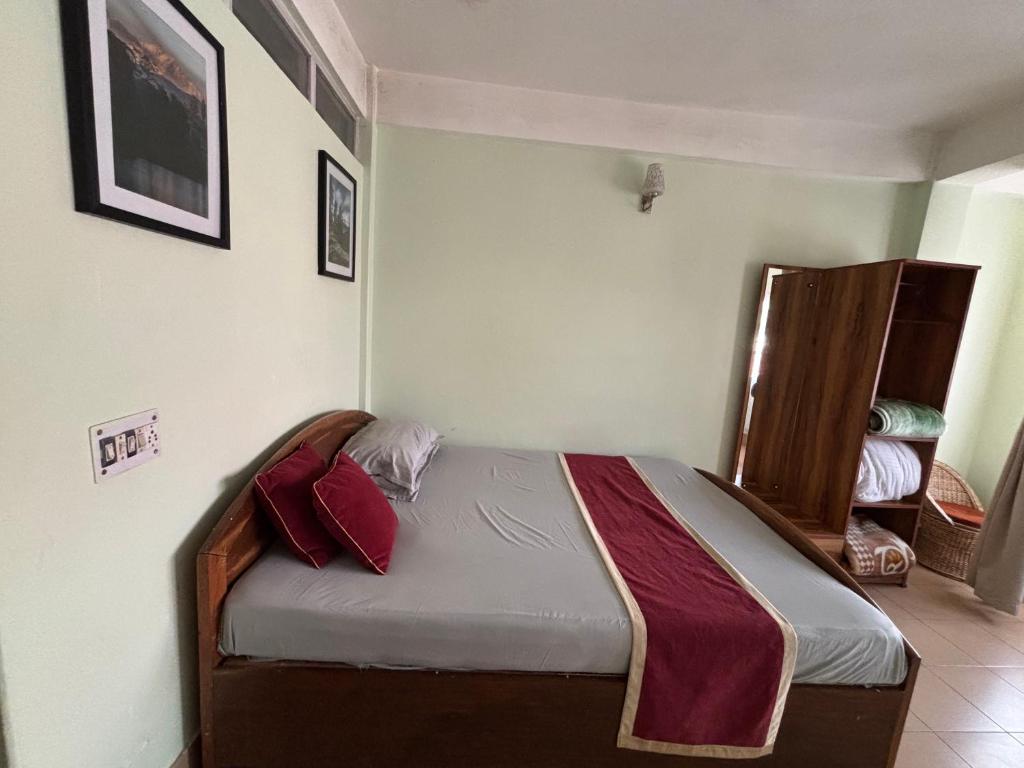 a bedroom with a bed with red pillows on it at The Parijat Inn in Mirik