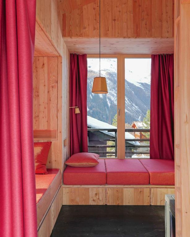 a room with red curtains and a large window at minipockethouse in Evolène