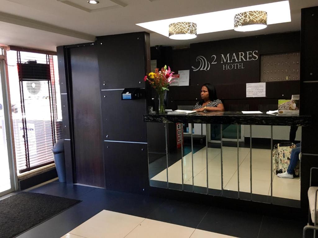 een vrouw die aan een balie in een wachtkamer zit bij Hotel 2 Mares in Panama-Stad