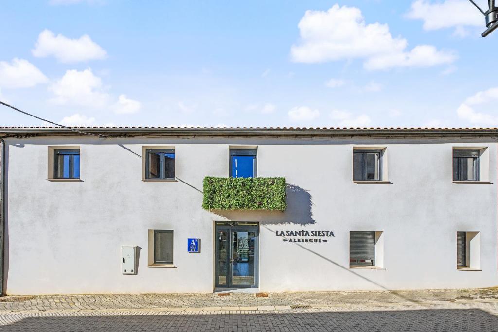 a white building with a blue door at Albergue La Santa Siesta in Villadangos del Páramo