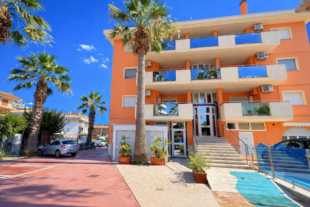 an orange building with palm trees in front of it at Appartamenti La Mer in San Benedetto del Tronto