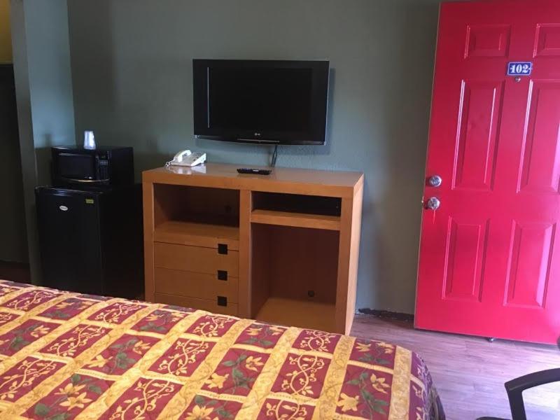 a bedroom with a bed and a tv and a red door at Townhouse Motel - West Sacramento in West Sacramento