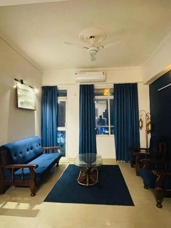 Vantage View - 2BHK Apartment في Nalmatha: غرفة معيشة بها أريكة زرقاء وطاولة زجاجية