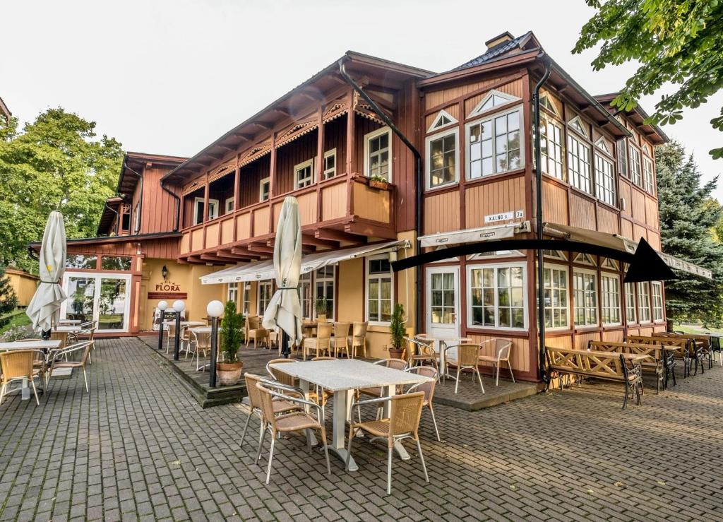 a building with tables and chairs in front of it at Vila Flora in Juodkrantė