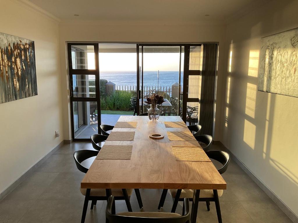 a long wooden table in a room with a large window at The Tarp at Whale Cove in De Kelders