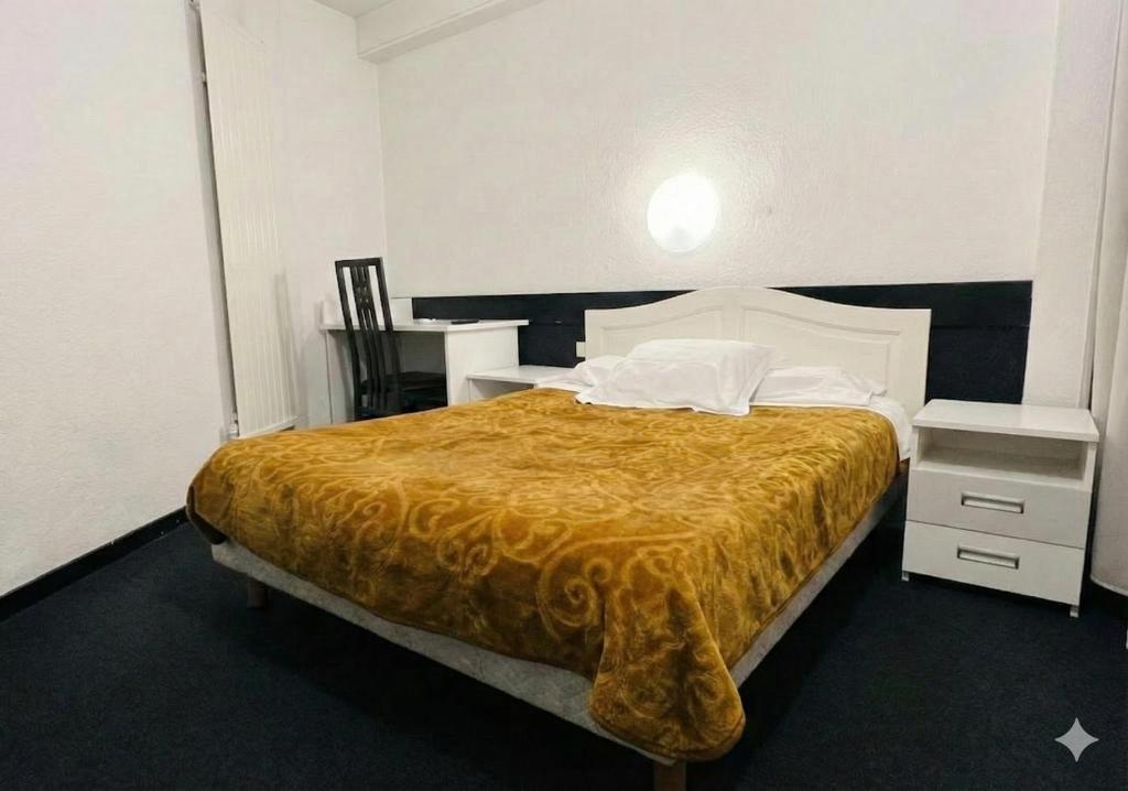 a bedroom with a bed with a orange bedspread at Hôtel La Palmeraie in Toulouse