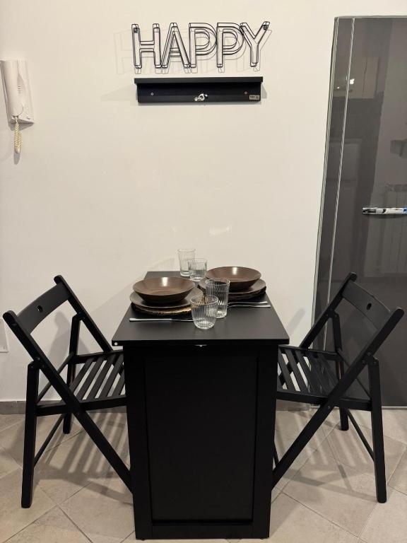 a black table with two chairs and a happy sign on the wall at NEpicentro2 in Nepi