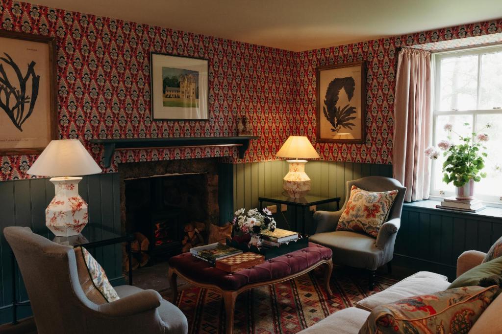 a living room with a fireplace and red wallpaper at Muir Cottage in Aboyne
